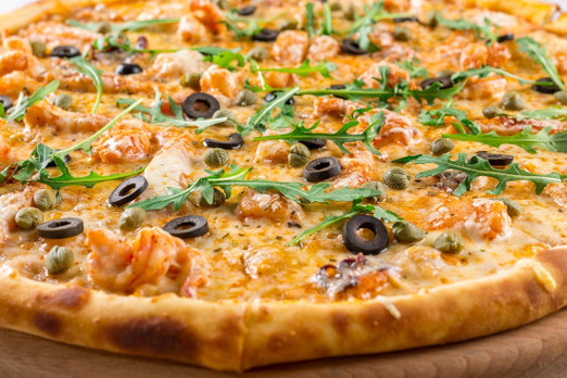 Pizza mit Oliven, Käse und frischen Kräutern auf knusprigem Teig